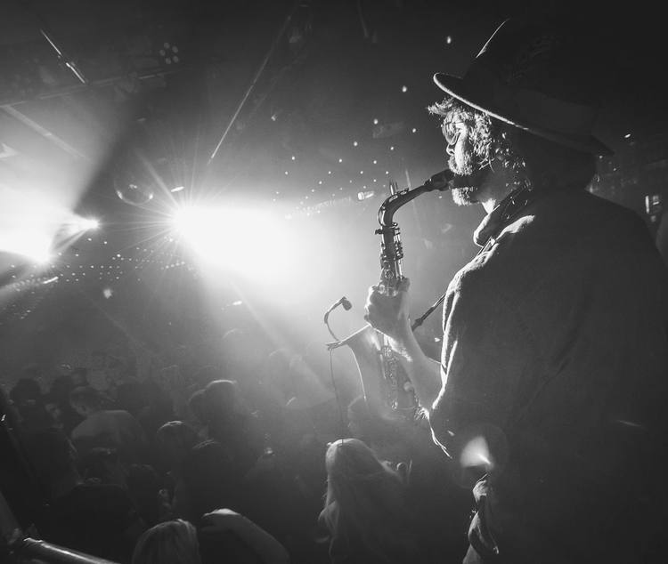 Saxophonist backlit on a club stage